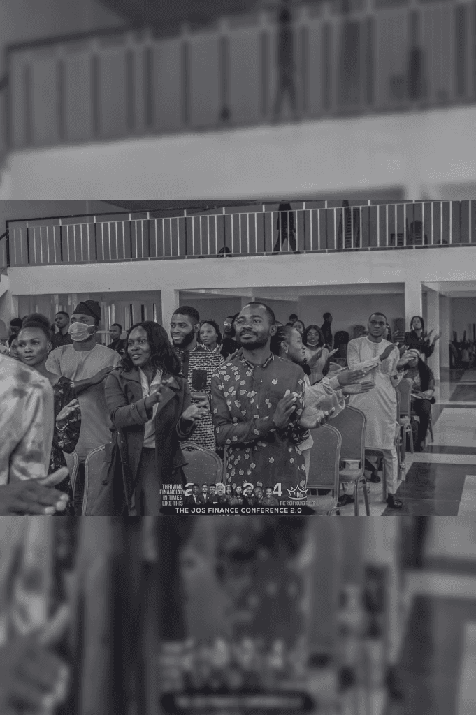 A man in a patterned shirt clapping enthusiastically in an audience.